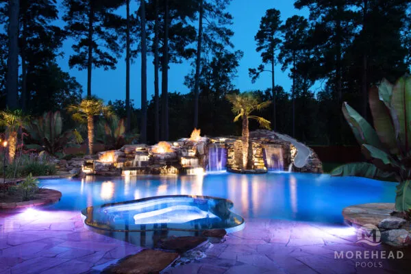 Luxury pool at night with fire features and blue lights