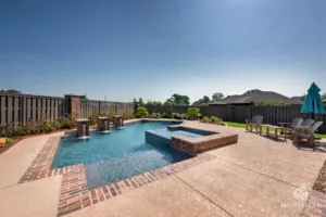Geometric swimming pool in backyard with custom spa